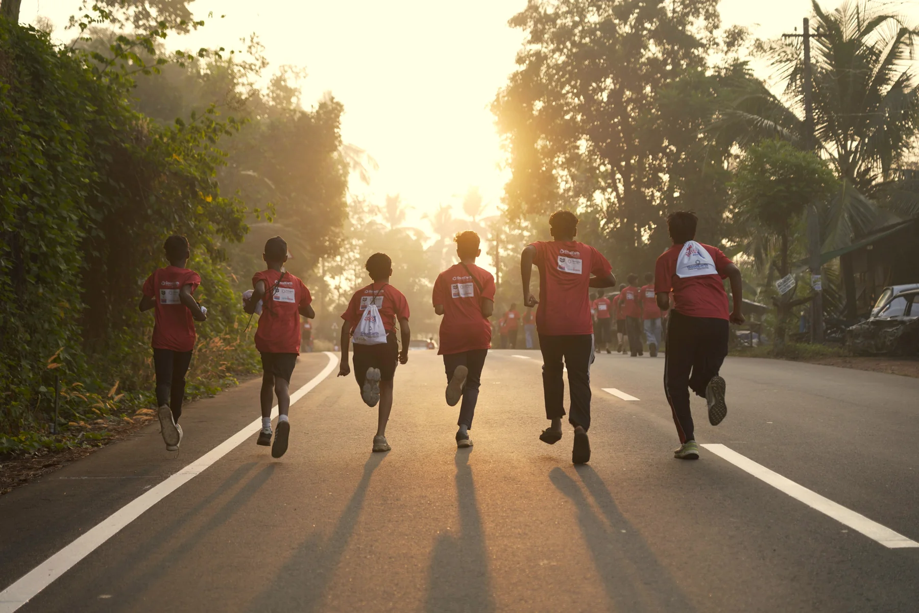 Runners moving along a Peravoor road at sunrise