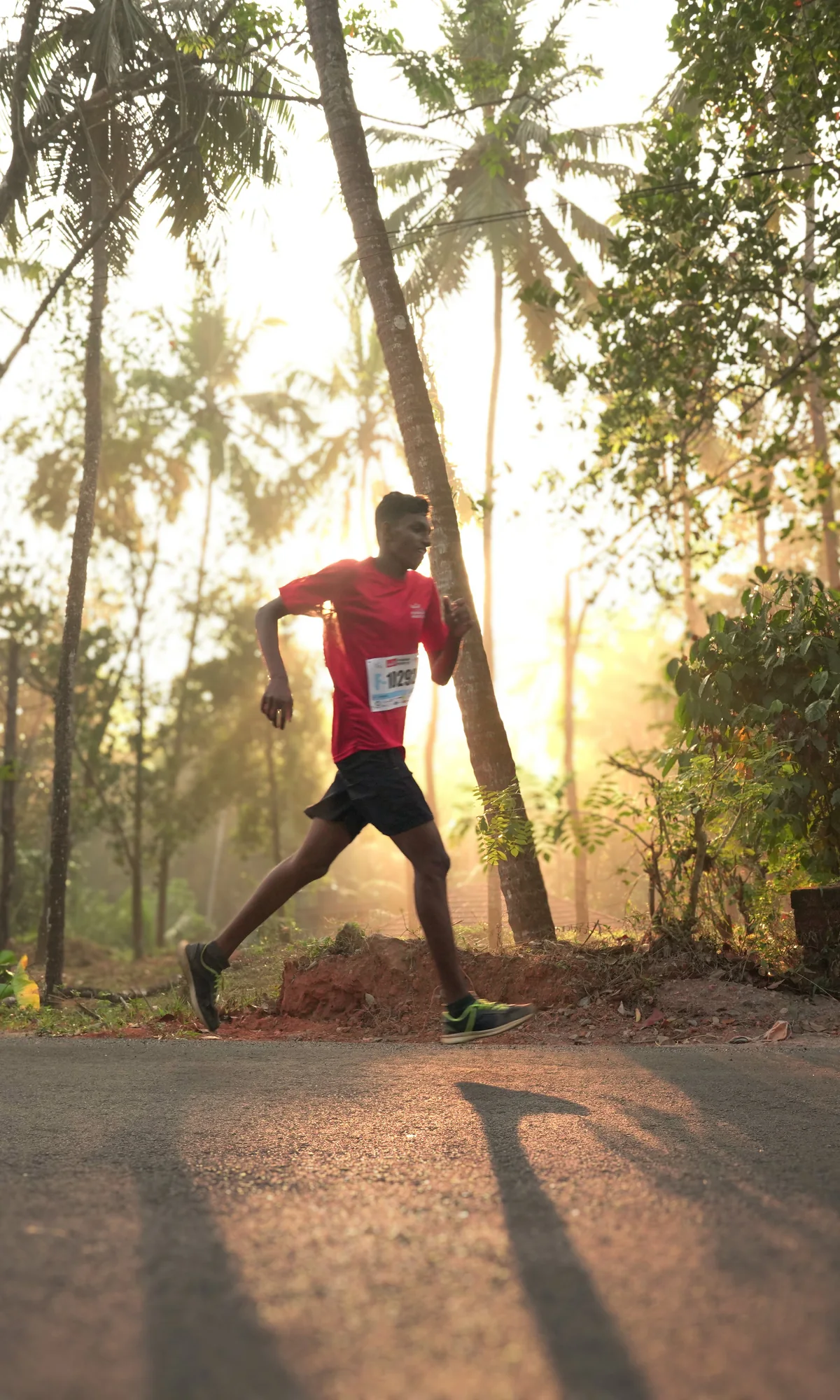 Runner crossing a sunlit road through Peravoor
